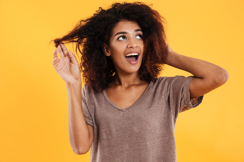 happy african woman touching her hair looking up