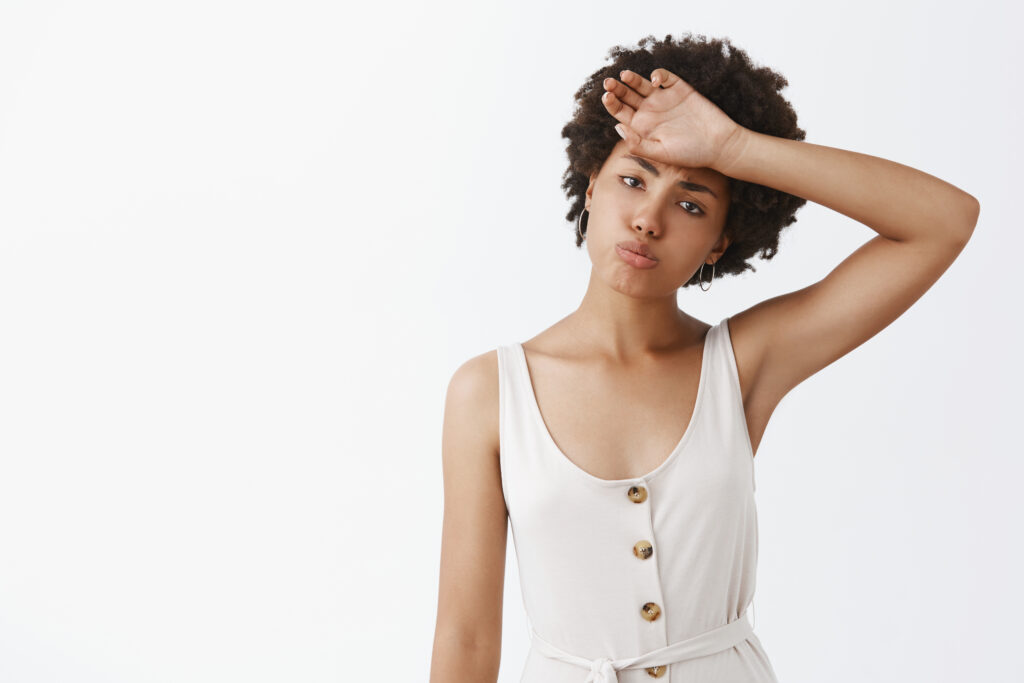 indoor shot tired gloomy good looking female entrepreneur white overalls with afro hairstyle whiping sweat out forehead pursing lips tilting head wanting rest after hard work 1