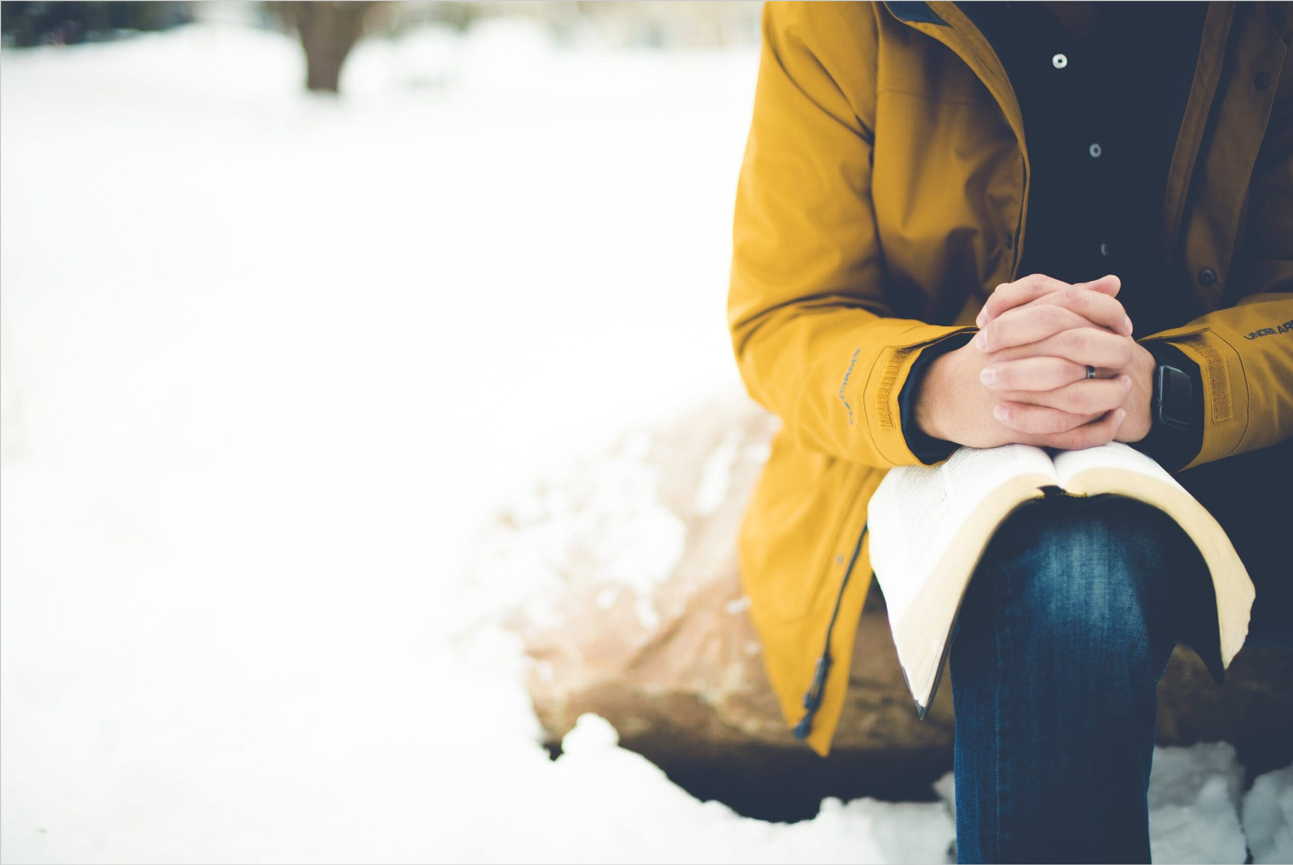 closeup shot person sitting rock with bible knee praying scaled